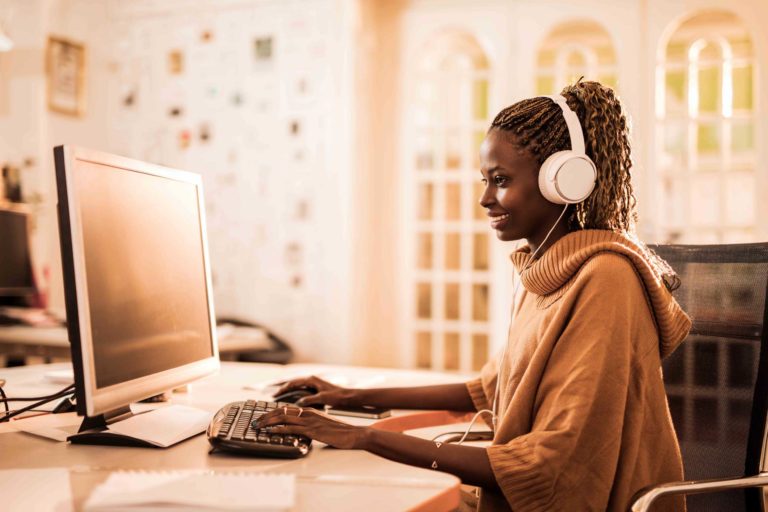 Happy African American customer service representative working on desktop PC.
