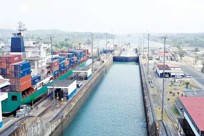 A large container ship passing through the neo-panamax locks, reflecting the new Panama Canal decarbonization roadmap initiatives.